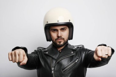 Deri ceketli genç bir motorcunun portresi beyaz arka planda izole edilmiş bir motosiklet sürüyormuş gibi yapıyor. Yatay.
