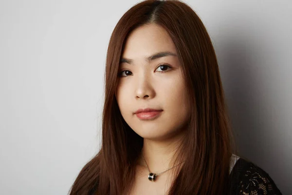 Vista laterale della giovane donna cinese con i capelli lunghi in posa sullo sfondo bianco. Isolato . — Foto Stock