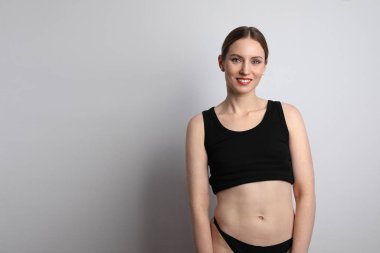 Siyah iç çamaşırı giyen, gülümseyen ve stüdyoda poz veren genç bir kadın.. 