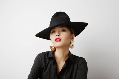 Beyaz arka planda poz veren ve moda kıyafetleri giyen Asyalı genç bir kadın. İzole edilmiş.