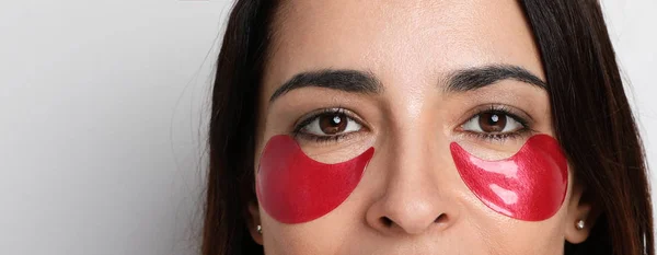 Young woman looking at camera take care of her skin with under eye patches. Isolated vertical. — Stock Photo, Image