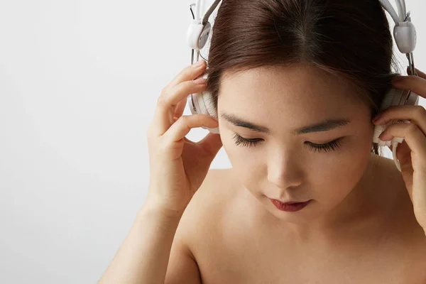 Ritratto laterale di donna cinese in posa sullo sfondo bianco con grandi auricolari. Isolato . — Foto Stock