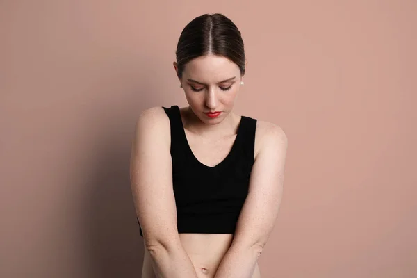 Jovem mulher vestindo roupa interior preta casual olhando para baixo e posando no estúdio . — Fotografia de Stock