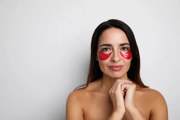 Mujer atractiva mirando a la cámara cuidar de su piel con parches debajo de los ojos. Espacio para tu texto . —  Fotos de Stock