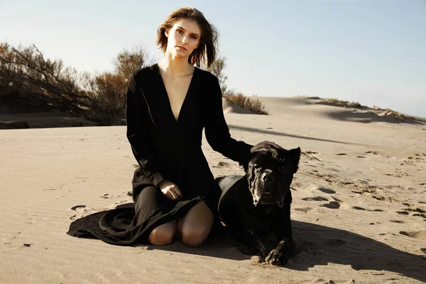 若い女性は犬と一緒にビーチで晴れた天気を楽しんでいます。屋外. — ストック写真