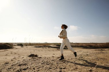 Genç bir kadın kış kumsalında eğleniyor. Açık havada..