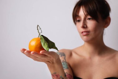 Şehirli portakal meyvesi tutan genç bir kadın. C vitamini kavramı.