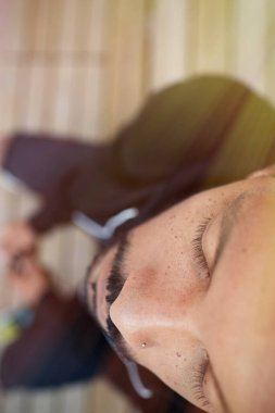 Çocuk parkında gözleri kapalı oturan genç siyahi adam. Dikey.