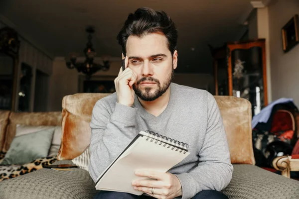 Joven barbudo hipster probando algo blanco en un cuaderno . — Foto de Stock