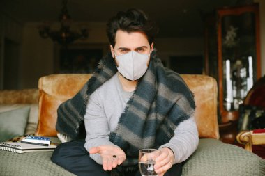 Genç sakallı adamın yakın plan portresi bir virüs kaptı ve tıbbi maske kullandı. Evde karantina.
