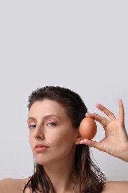 Elinde bir yumurta olan çekici bir kızın yakın plan portresi. Dikey.