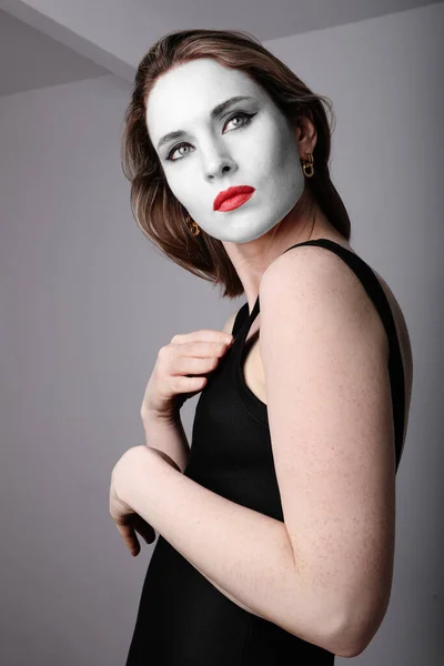 Atraktivní a sexy dívka s obličejovou maskou a červenými rty pózující ve studiu. Svisle. — Stock fotografie