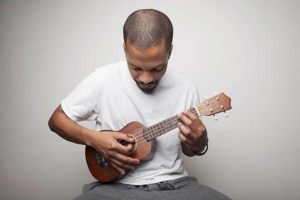 Orang Afrika bermain ukulele terisolasi pada latar belakang putih. — Stok Foto