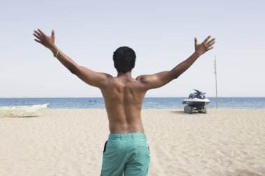 Siyah erkek vesikalığı, boş zamanlarını mavi denize karşı durarak geçirdiği için mutlu..