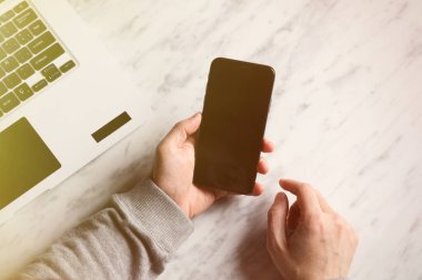 Mermer yüzeyde el kameralı akıllı telefon ve dizüstü bilgisayarın bir kopyası..