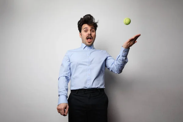 Bilde av en alvorlig ung mann som holder tennisball mens han sitter i embetet . – stockfoto