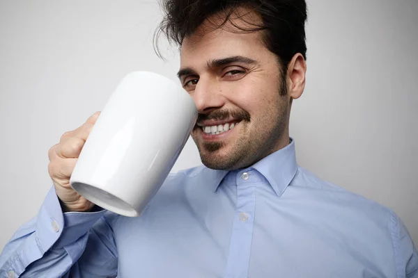 Közelkép portré fiatal szakállas férfi iszik csésze kávét fehér háttér nagyon boldog és izgatott. — Stock Fotó