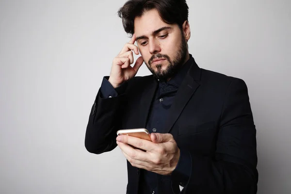 Komoly szakállas üzletember használ okostelefon öltöny a fehér háttér. — Stock Fotó