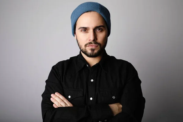 Retrato lateral de hipster barbudo con sombrero azul y camisa mirando a la cámara . — Foto de Stock