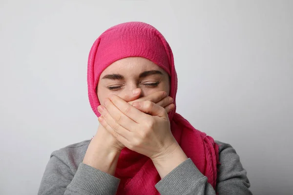 Jovem muçulmana vestindo um véu, cobrindo a boca com as duas mãos e chorando, de pé sobre um fundo branco . — Fotografia de Stock