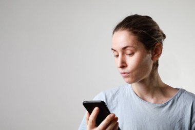 Yaşam tarzı vesikalıklı kadın telefondaki akıllı telefon uygulamasında mesaj atıyor. 20 'li yaşlarda beyaz bir kadın model..