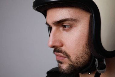 Kasklı yakışıklı sakallı adam beyaz arka planda ve ciddi bir yüzü var.. 