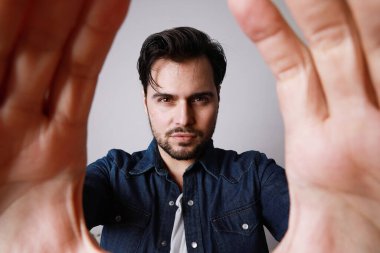 Eli kameraya yakın olan, beyaz arka planda izole edilmiş genç sakallı adama yakın durun..