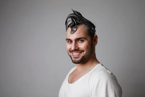 Pria berjenggot bahagia tersenyum dan berpose di atas latar belakang abu-abu dengan rambut basah. Konsep perawatan rambut. — Stok Foto