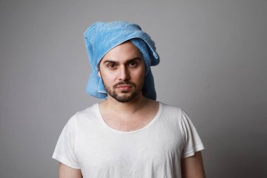 Kafasına havlu sarıp beyaz tişört giyen sakallı bir adam. Gri saç bakım konseptinde izole edilmiş..