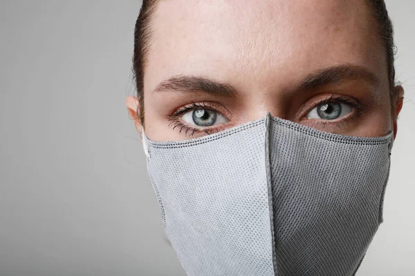 Close-up portrait of young woman in medical face protection mask indoors on white background. Protection of the virus.