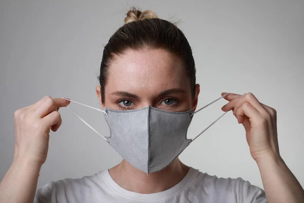 Portret młodej kobiety w masce ochrony twarzy w pomieszczeniu na białym tle. Ochrona wirusa. — Zdjęcie stockowe