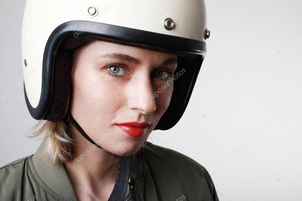 Close-up portrait of woman with red lips in militar jacket looking at camera. White background. Motor, extreme.