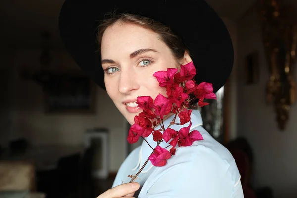 Retrato lateral de mulher jovem tem um rosto emocional e bom humor e vestindo chapéu e segurando flores silvestres . — Fotografia de Stock