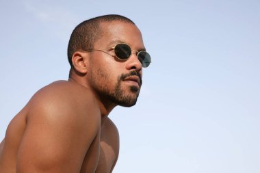 Dışarıda, sakallı, güneş gözlüğü takan yakışıklı bir adamın plajda vakit geçirdiği portresi..