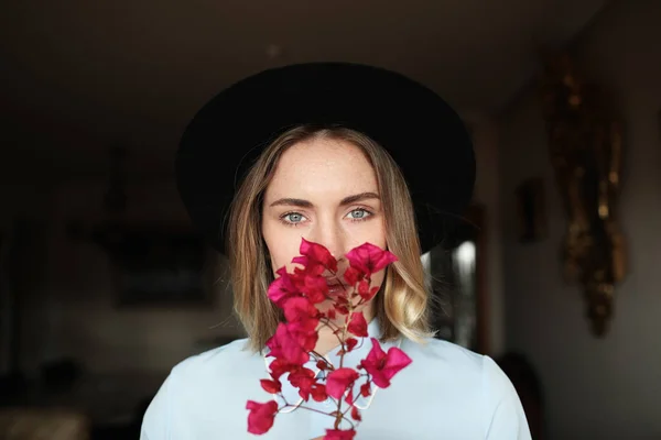 Jovem mulher tem um rosto emocional e bom humor e vestindo chapéu e segurando flores silvestres . — Fotografia de Stock