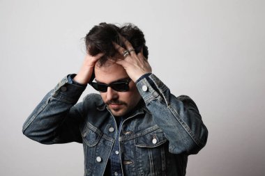 Ciddi ve şık bir adamın portresi kendine güvenen bir ifadeyle düz görünür, kot ceket giyer, izole olur..