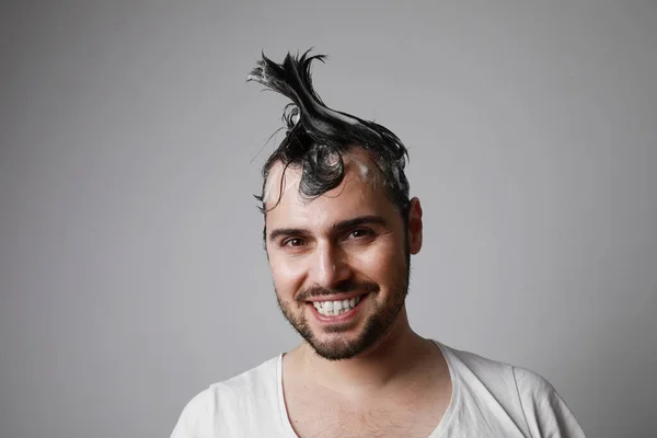 Pria berjenggot bahagia dengan wajah gembira dan berpose di atas latar belakang abu-abu dengan rambut basah. Konsep perawatan rambut. — Stok Foto
