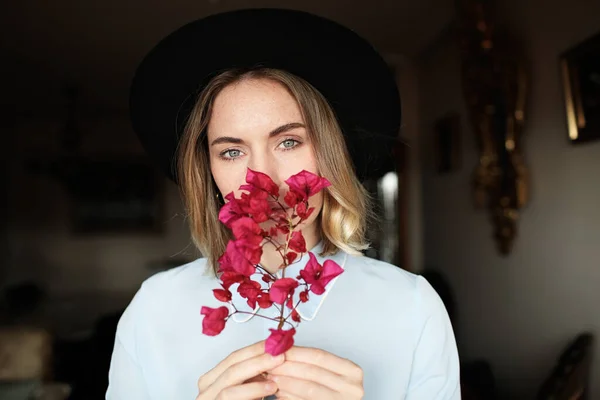 Jovem mulher tem um rosto emocional e bom humor e vestindo chapéu e segurando flores silvestres . — Fotografia de Stock