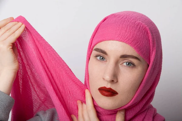 Close-up portrait of a young muslim woman wearing a head scarf hijab and trying to fix it. Isolated. — Stock Photo, Image