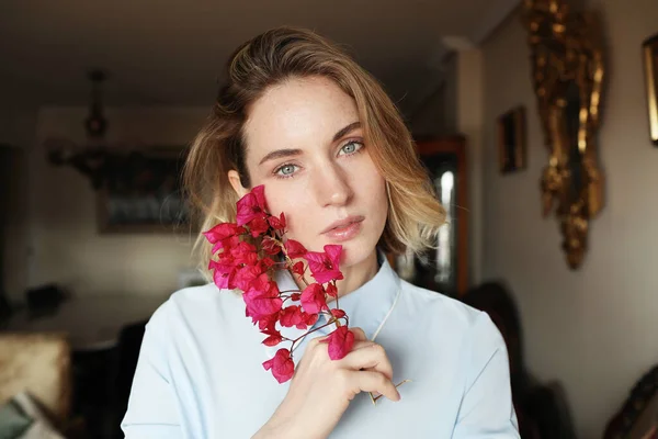 Jovem mulher tem um bom humor e vestindo camisa azul e segurando flores silvestres . — Fotografia de Stock