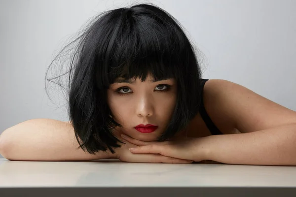 Ázsiai nő sötét hajjal, egyenesen a kamerába néz, fehér háttérrel pózol. Szépségkoncepció — Stock Fotó