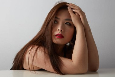 Çekici Asyalı genç bir kadının portresi, el ele tutuşuyor, koyu renk kulakları var, beyaz arka planda izole edilmiş..