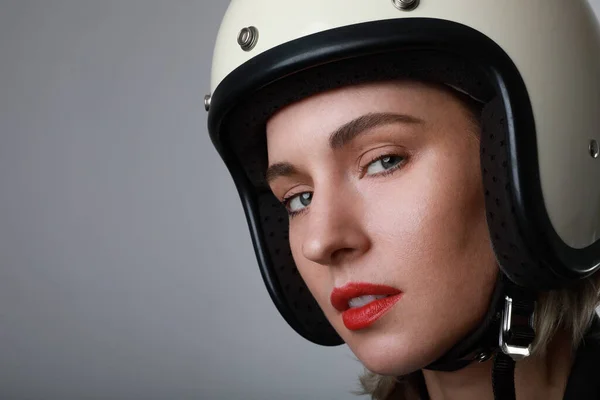 Close-up portrait of biker young woman, wearing white helmet, with red lips. Blue background. Space for your text.