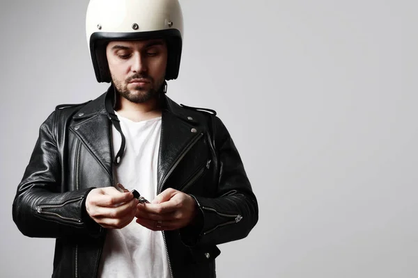Egy szakállas motoros férfi retro fehér sisakban és motorkulcsokkal a kezében. Szabad hely a szövegnek. — Stock Fotó