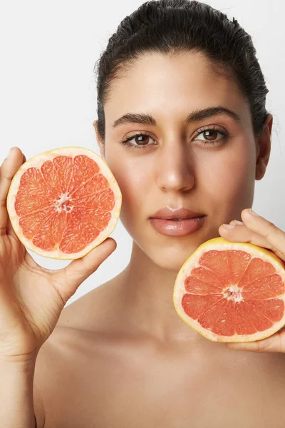 Verticaal portret van jonge mooie vrouw met twee sinaasappels poserend over witte achtergrond. Gezond en schoon eten. — Stockfoto
