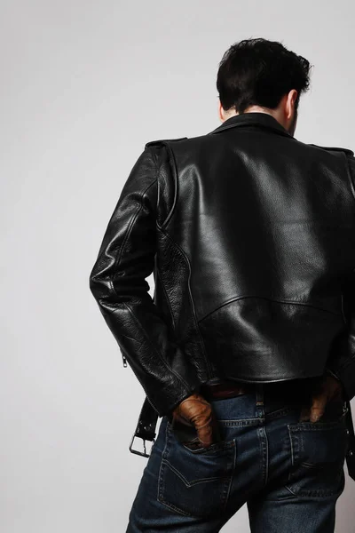 Silhouette of a European bearded man from the back in a biker jacket look to the side. Space for text. Vertical shot.