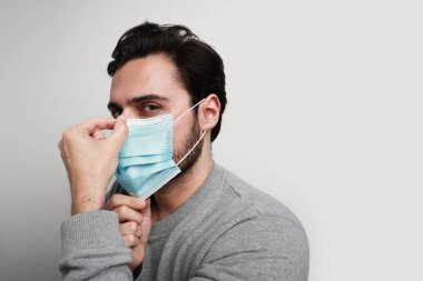 Koronavirüs için tıbbi maske takan genç bir adamın yan portresi. Dünya çapında bir salgın var. Metin için boşluk.