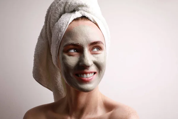 Portré gyönyörű fiatal nő néz félre alkalmazása agyag arc maszk, csomagolás törölköző a fej bőrápoló kezelés koncepció. — Stock Fotó