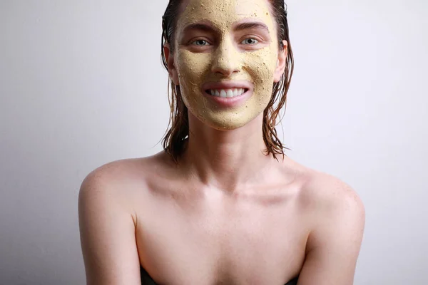 Portrait de femme heureuse avec masque facial hydratant avec sourire mignon isolé sur fond gris. Beauté et soin de la peau . — Photo