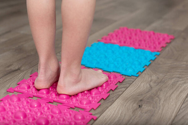 Baby feet are standing on orthopedic rug